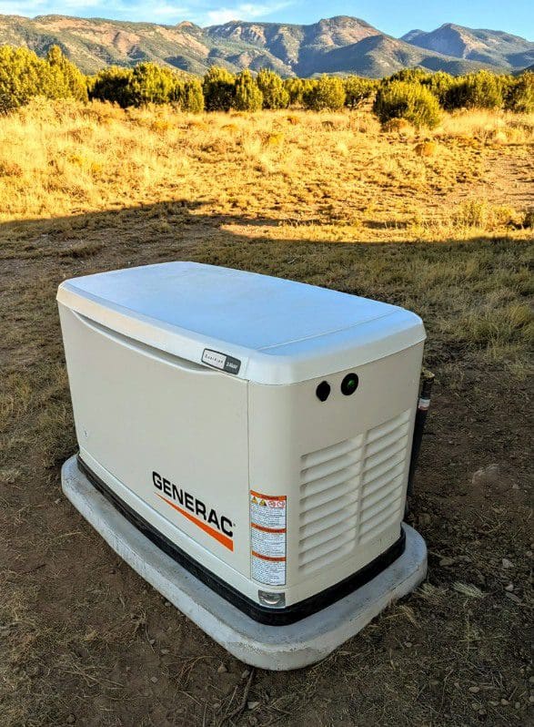 A white generator sitting in the middle of a field.